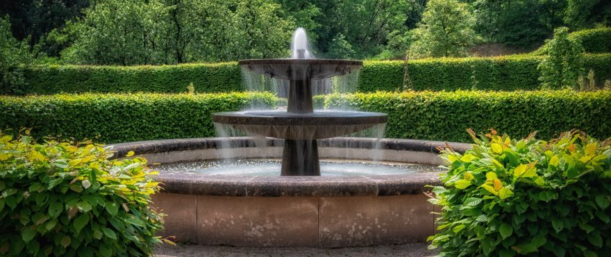 An ornate water fountain set within a well landscaped garden.