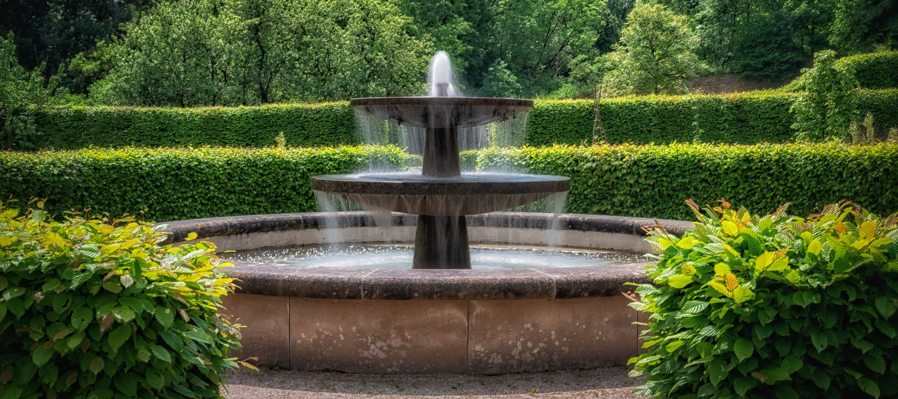 An ornate water fountain set within a well landscaped garden.